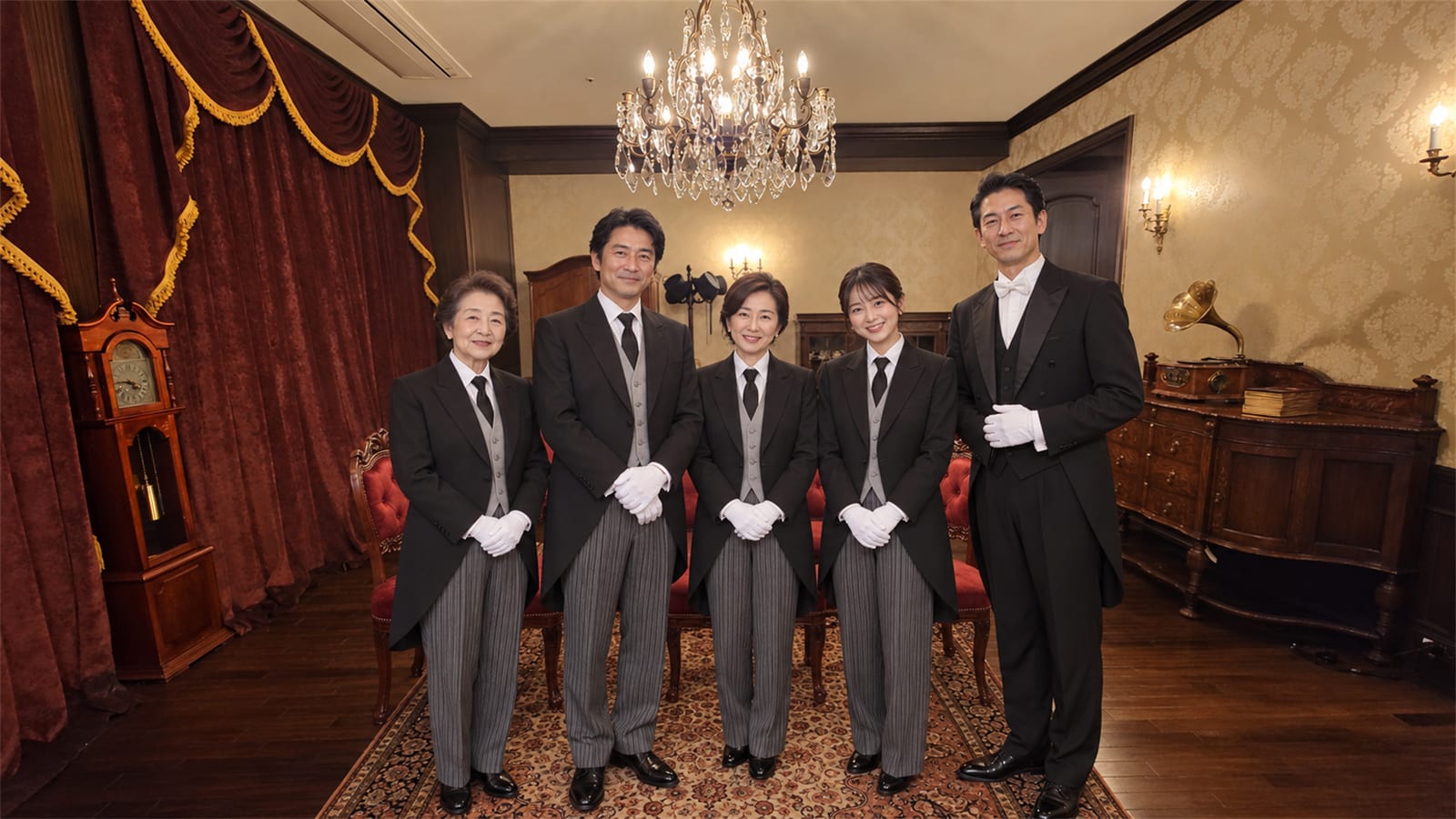 正餐の間で、祖母・父・母・娘の一家がモーニングコート姿で記念撮影する