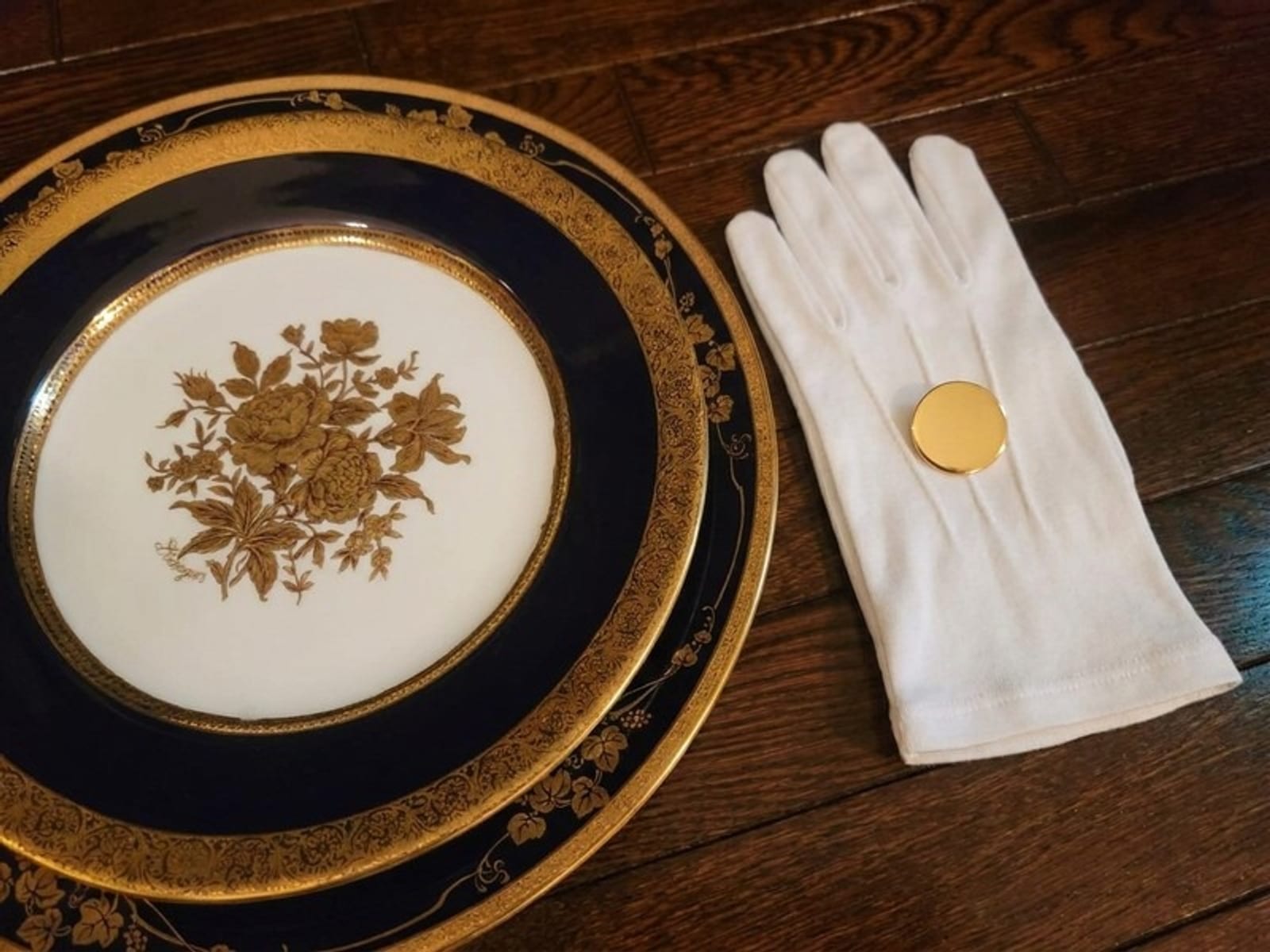 日本執事アカデミーの公式サイトより。金彩の洋皿に重ねて置かれた、金の徽章を添えた白手袋