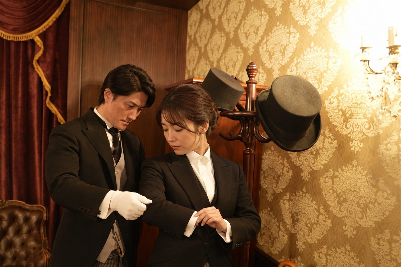 衣装部屋でモーニングコートの着付けを受けるご主人さまと執事